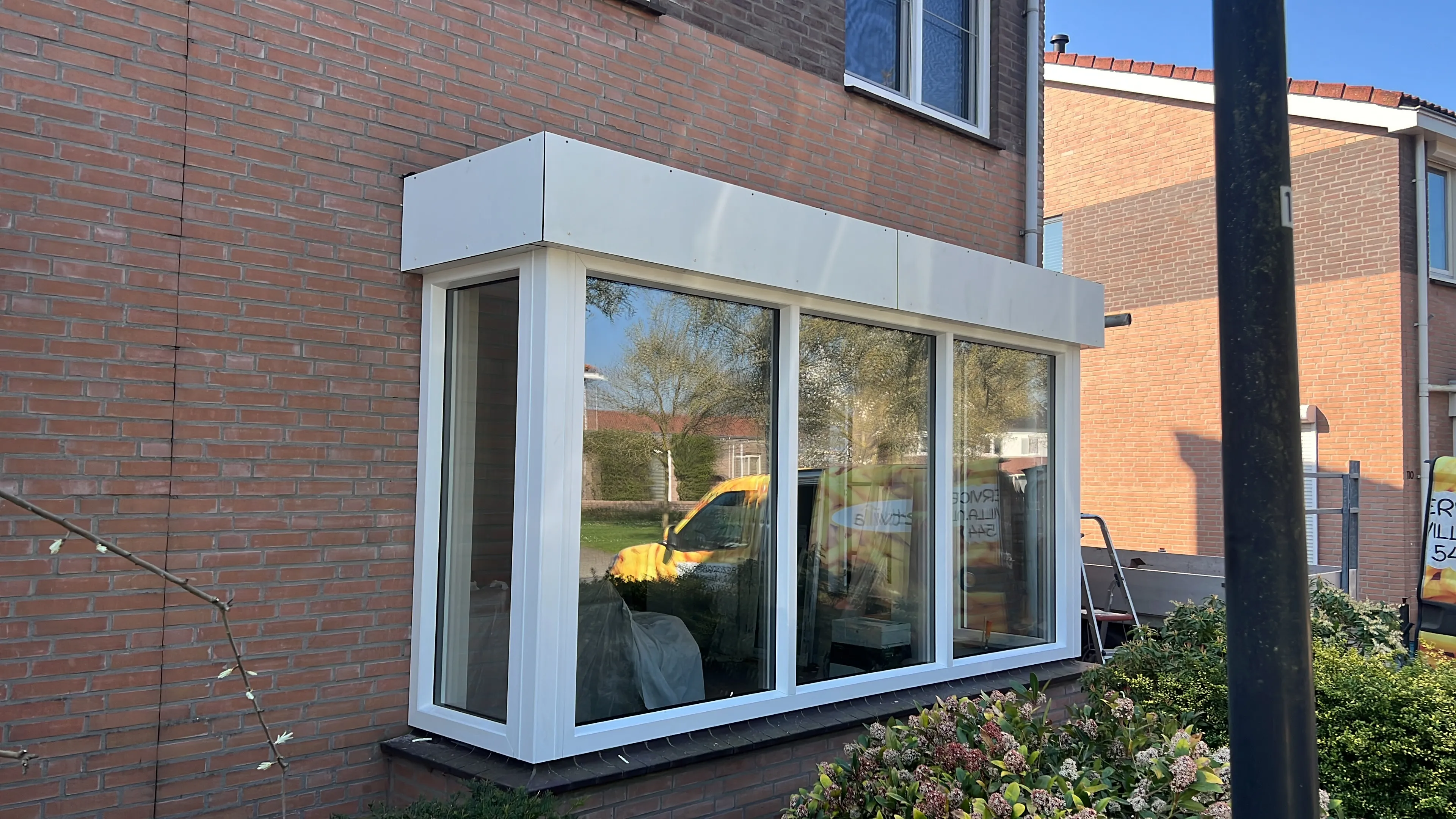 Lichte erker met brede glasvlakken in een bakstenen gevel